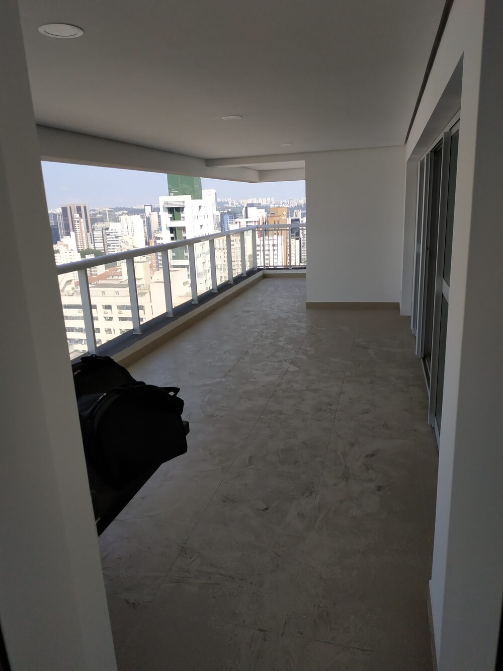 Apartamento Pinheiros antes — varanda em obra bruta com vista para SP