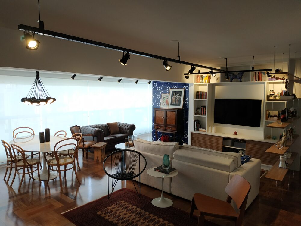 Apartamento Pinheiros depois — sala integrada com trilho de luz e taco de madeira