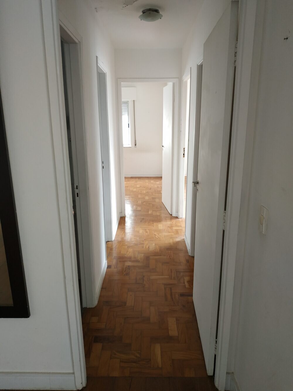 Apartamento Higienópolis antes da reforma — corredor original com piso de taco
